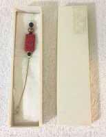 Full view of the vintage cinnabar style hat pin in its box, showing the pin and the decorative beads clearly.