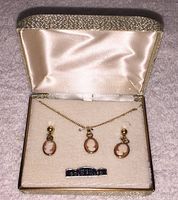 Set in original box with satin and velvet lining, showing necklace and earrings with cameo designs and gold-filled label.