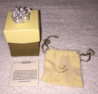 Photo of the ring on its box along with the Lenox branded pouch and a care instruction booklet.