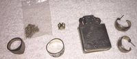 Full view of all items: two rings, chain, lighter, lapel pin, and earrings.
