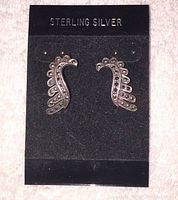 Photo of two new sterling silver pierced earrings on original black card labeled 'STERLING SILVER'. Earrings have a curved feather or leaf motif with small dot detailing.