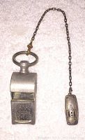 Full view of vintage metal Signal Police whistle attached to a chain connected to a sterling clip marked with a B.