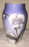 Front view of a porcelain vase with white floral painting on a lavender gradient background.