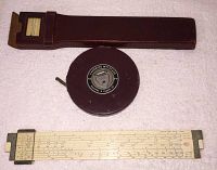 Photo of leather-cased round Kuffel & Essex 100ft tape measure and Post Versalong Hemmi slide rule laid flat.