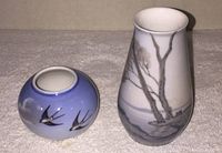 Photo showing the two small vases side by side, blue Royal Copenhagen vase with bird motif on the left, taller Bing & Grondahl vase on the right with black and white tree design.