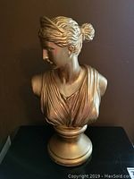 Front angle photo showing the bust's detailed facial features, draped garment, and gold-tone finish.