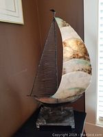 Full view of decorative sailboat sculpture showing metal frame and mother of pearl sails.
