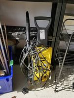 Full view of the yellow Karcher pressure washer with attached cord and hose, showing general condition and portability features