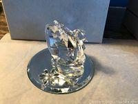 Close-up photo of one clear Australian crystal swan figurine seated on a round mirrored base. The swan is faceted and has a small colored gem eye.