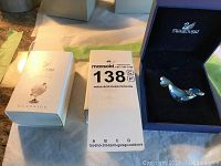 Photo showing one Swarovski crystal seal figurine in the official box with brand name visible, alongside the original packaging box.