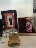 Photo showing abalone inlay box, fabric jewelry drawers, wooden green felt lined box, gold-tone metal box, framed art piece, wooden book box