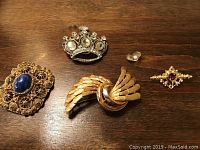 Four brooches and a loose clear glass cabochon on wood surface