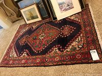 Full view of rug laid on carpet with framed art on top
