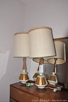 Photo of two retro table lamps with beige shades on wooden surface against wall, showing overall style and height.