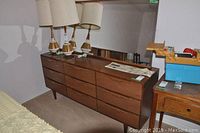 Front view of nine-drawer dresser with lamps on top and mirror behind