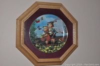 Close-up of the framed M.I. Hummel "Little Companions" collector plate in octagonal wooden frame.