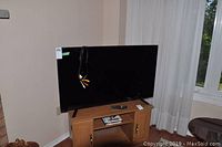 Full front view of 48" TV on wooden stand with attached composite cables