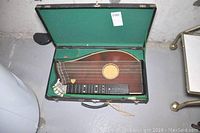 Top view of zither inside open hardshell case with green felt lining