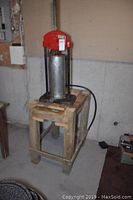 Full view of the sausage press mounted on a wooden stand with caster wheels, showing overall size and setup.