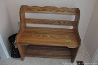 Wooden hall bench front view showing the carved backrest and storage shelf below seat.