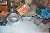 Photo of assorted crates including wooden with vintage branding, plastic milk crates in green and blue, metal tubs, and small metal box.