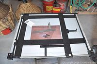 Top view of adjustable drafting board on metal stool, showing measurement grid and angle adjustment handles