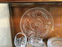 Photo showing large round platter with embossed fruit designs, glass swan dish, and glass basket dish.