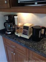 Photo of the three appliances on the counter: Black & Decker coffee maker, Sears food processor, Bodum electric kettle.