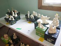 Display of multiple Department 56 Snowbabies figurines on a table with original boxes and decorative elements.