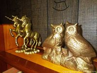 Pair of brass unicorn and owl bookends on wooden surface with dark textured background