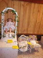 Wide view of all three dolls: one large doll on swing and two smaller dolls in bassinets