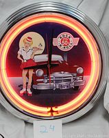 Front view of the 1950s rock n' roll neon wall clock with neon light on.