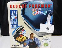 Front view of original box showing George Foreman Blue Color Grill and marketing text including 'Lean Mean Fat-Reducing Machine' and fat reducing claims.