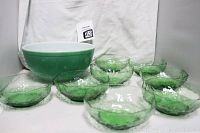 Eight small translucent green textured glass bowls arranged in front of the large green and white ceramic bowl.