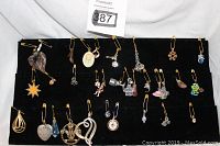 Photo of 22 assorted vintage pendants displayed on a black velvet holder