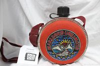 Front view of vintage Marlboro Unlimited cigarette advertising canteen with colorful logo, black cap, and red fabric cover.