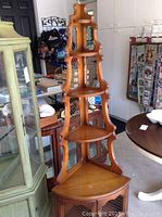 Full view of tall solid wood corner shelf with multiple shelves and wire mesh decorative panels