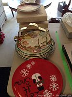 Stack of multiple plates with one colorful detailed plate and red plate on top