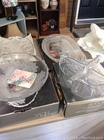 Two glass trays and two glass bowls on their original boxes and some surrounding items.