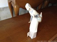 Porcelain figurine showing full figure of woman with basket and lamb at feet