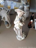 Full view of Lladro NAO porcelain boy figurine holding a bird and wearing a hat.