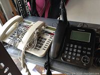 View of three telephones including two Bell and one Panasonic phone showing overall condition and setup.