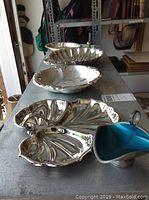 Two silverplate candy dishes with scalloped design on a shelf