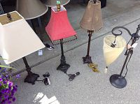 Four table lamps arranged on the floor showing their shades and cords, highlighting the variety of styles and lamps.