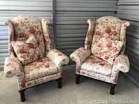 Two oversized floral wingback chairs side by side in storage unit