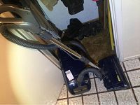 Kenmore canister vacuum cleaner with hose, wand, and power nozzle placed on tiled floor near white walls and cabinets.