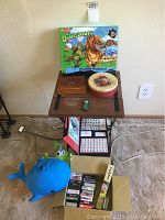Wide view of all items on and under a small table including puzzle, boxes, cards, toy truck, and plush whale.
