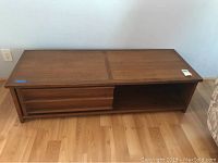 Full front view of the coffee table showing both the open cubby and sliding door cabinet storage.