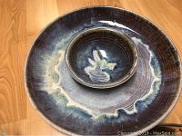 Photo showing a large hands-thrown pottery bowl with rich blue, purple and cream glazes with a smaller matching bowl nested inside it, highlighting the hand-glazed artistic finish.