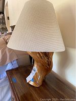 Front view of 26 inch driftwood lamp with white textured fabric shade on wooden table.